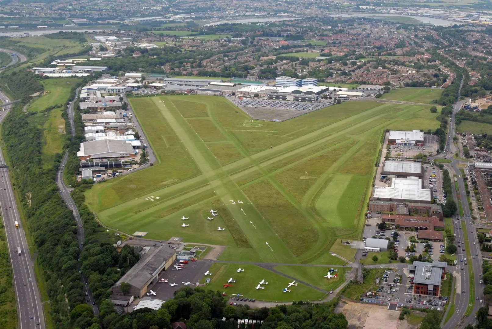 Aerial view of Rochester Airport, its grass runways and parked light aircraft